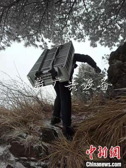 技術(shù)人員冒著風雪攀爬上陡坡 王政 攝
