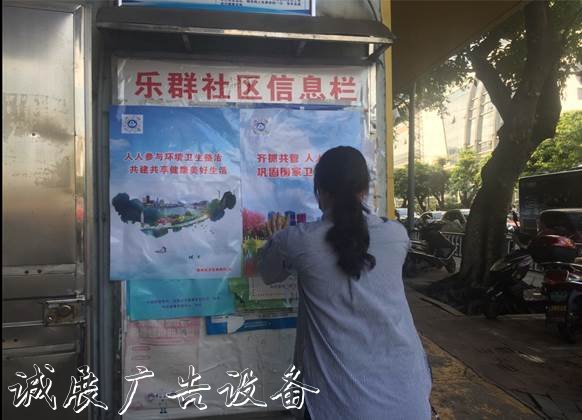圖為社區(qū)工作人員在宣傳欄粘貼創(chuàng)城海報(bào)